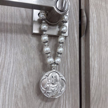 Cargar imagen en el visor de la galería, Bendición de hogar Llena de Gracia con perlas beige y medallón de rodio de Jesús y María colgada en una puerta