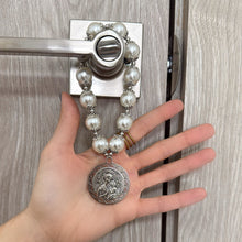 Load image into Gallery viewer, Bendición de hogar Llena de Gracia con perlas blancas y dije de la Virgen María en rodio colgada en una puerta
