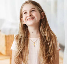 Cargar imagen en el visor de la galería, Niña sonriente luciendo el collar Mi Primera Cruz de Llena de Gracia en plata chapada en oro 18k