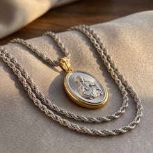 Load image into Gallery viewer, Collar Llena de Gracia con dije del Sagrado Corazón en plata esterlina y marco chapado en oro 18k sobre tela beige.