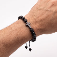 Cargar imagen en el visor de la galería, Pulsera Llena de Gracia de ónix negro con dije de cruz en muñeca masculina, diseño ajustable y elegante.