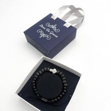 Cargar imagen en el visor de la galería, Pulsera Llena de Gracia de ónix negro con dije de cruz en caja de regalo azul con lazos de seda
