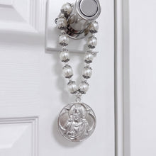 Cargar imagen en el visor de la galería, Bendición de hogar Llena de Gracia con perlas beige y medalla de rodio de Jesús y María colgada en una puerta
