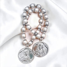 Cargar imagen en el visor de la galería, Bendición de hogar Llena de Gracia con perlas beige y medallas de rodio de Jesús y María sobre tela satinada blanca.
