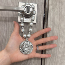 Cargar imagen en el visor de la galería, Bendición de hogar Llena de Gracia con perlas beige y medallón de rodio de Jesús y María colgada en una puerta.
