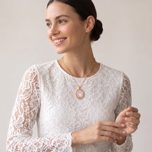 Load image into Gallery viewer, Modelo sonriente luciendo collar Llena de Gracia con medalla de Sagrado Corazón en madre perla y borde de perlas.
