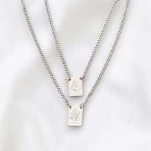 Load image into Gallery viewer, Collar unisex Llena de Gracia con dos mini escapularios de acero quirúrgico bañado en rodio sobre fondo blanco
