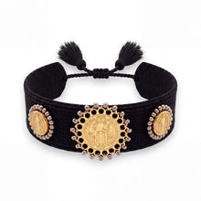Cargar imagen en el visor de la galería, Pulsera Llena de Gracia tejida en hilo negro con tres dijes de San Benito en baño de oro 18k y detalles de borlas.
